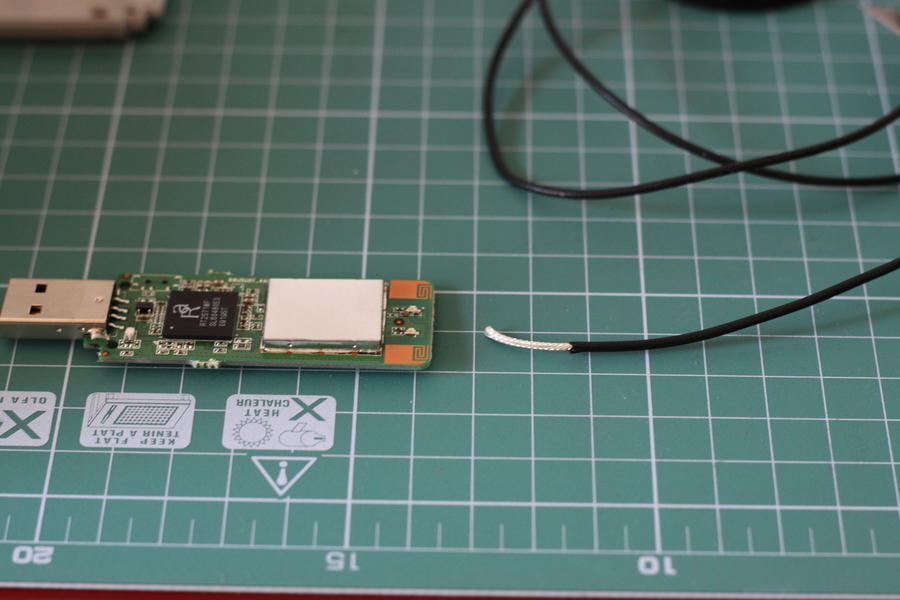 WiFi Adapter PCB next to an antenna cable cut and prepared to be soldered